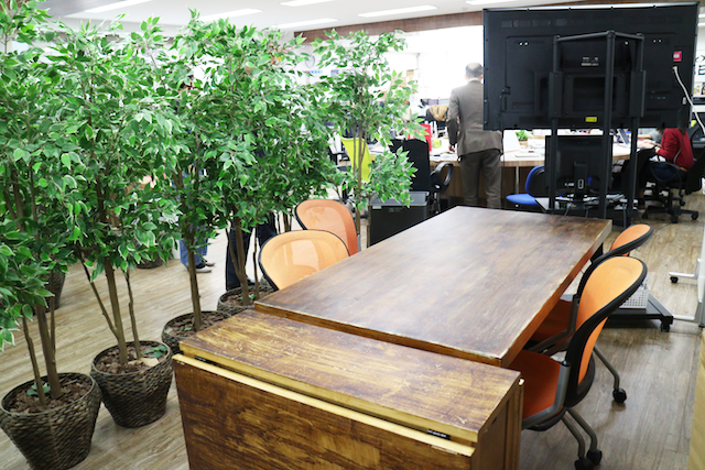 木目を活かした落ち着きのあるテーブルは、社員の休憩スペースに活用されているとのこと。手作りの温かみも感じられる。オシャレ。カフェかよ